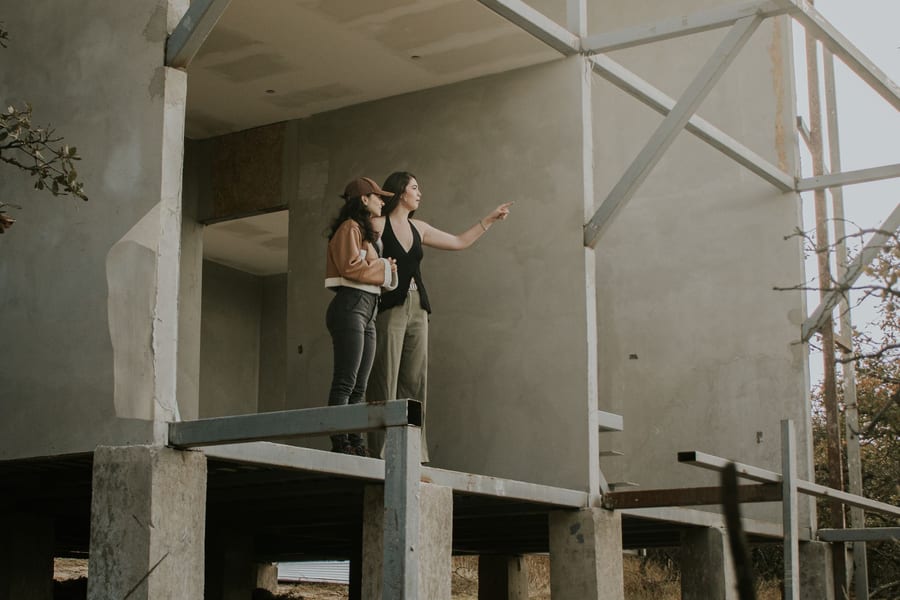 Duas pessoas numa casa de betão em construção, a observar a obra